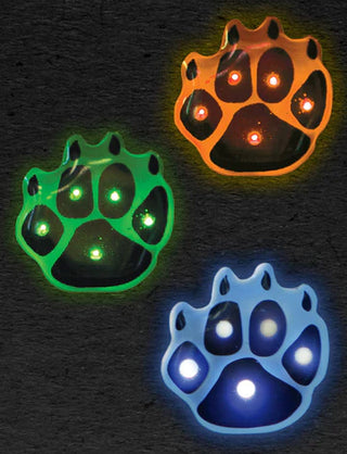 Three glowing paw-shaped lights in green, orange, and blue on a dark background.